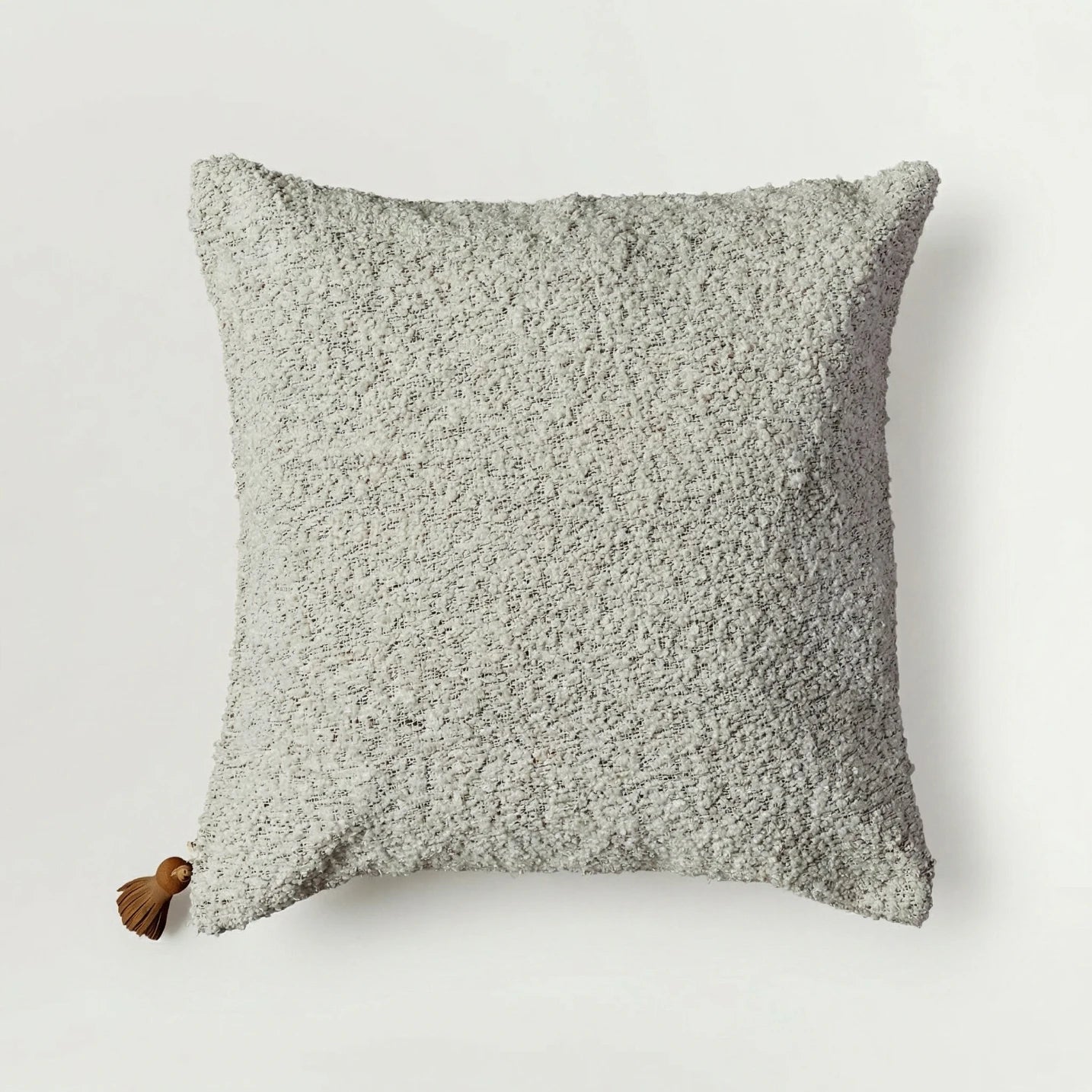 Textured gray pillow with a tassel on a light gray background