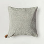 Textured gray pillow with a tassel on a light gray background