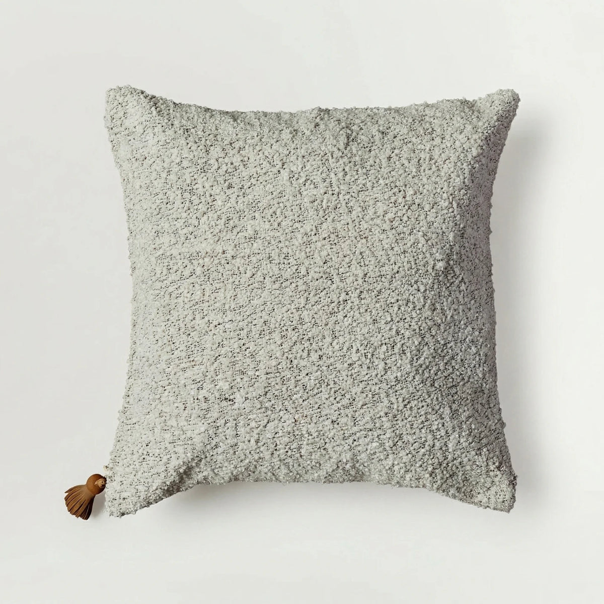 Textured gray pillow with a tassel on a light gray background