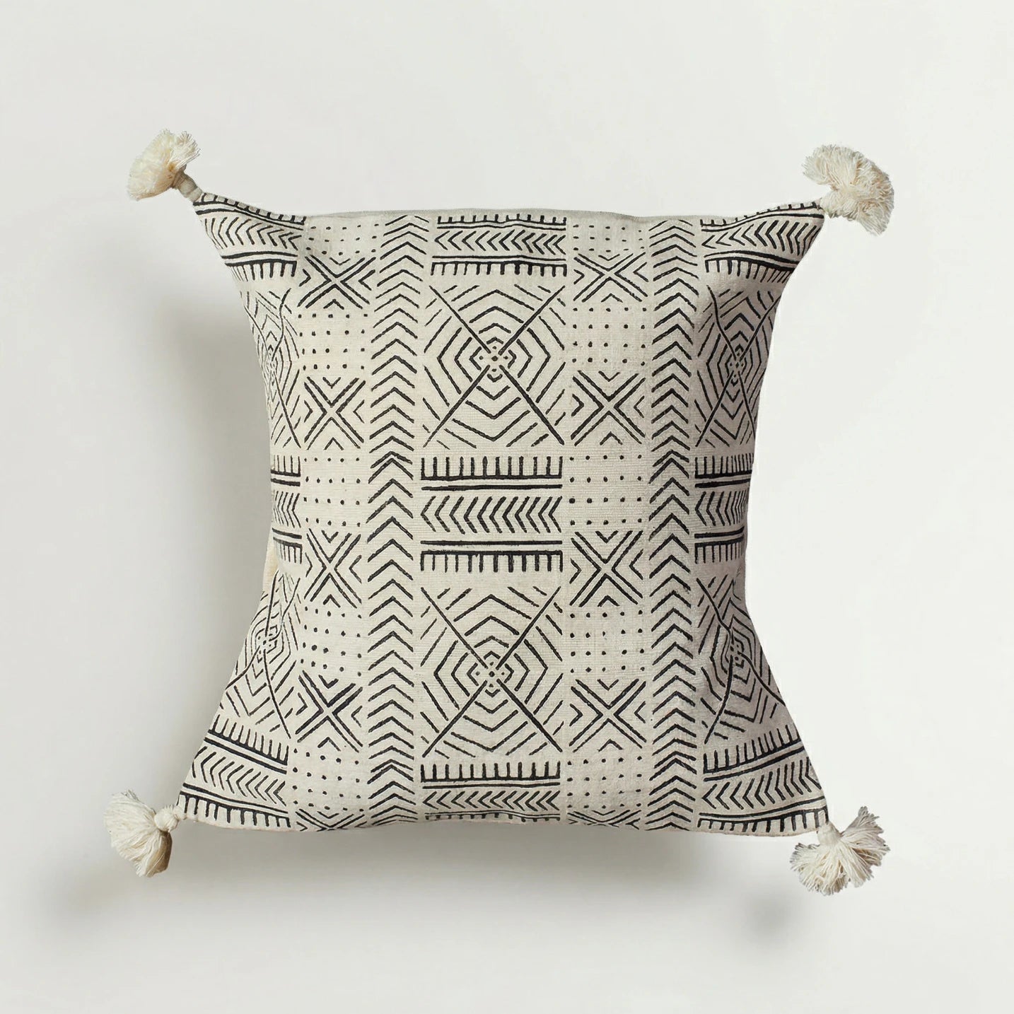 Decorative pillow with geometric pattern and tassels on a white background