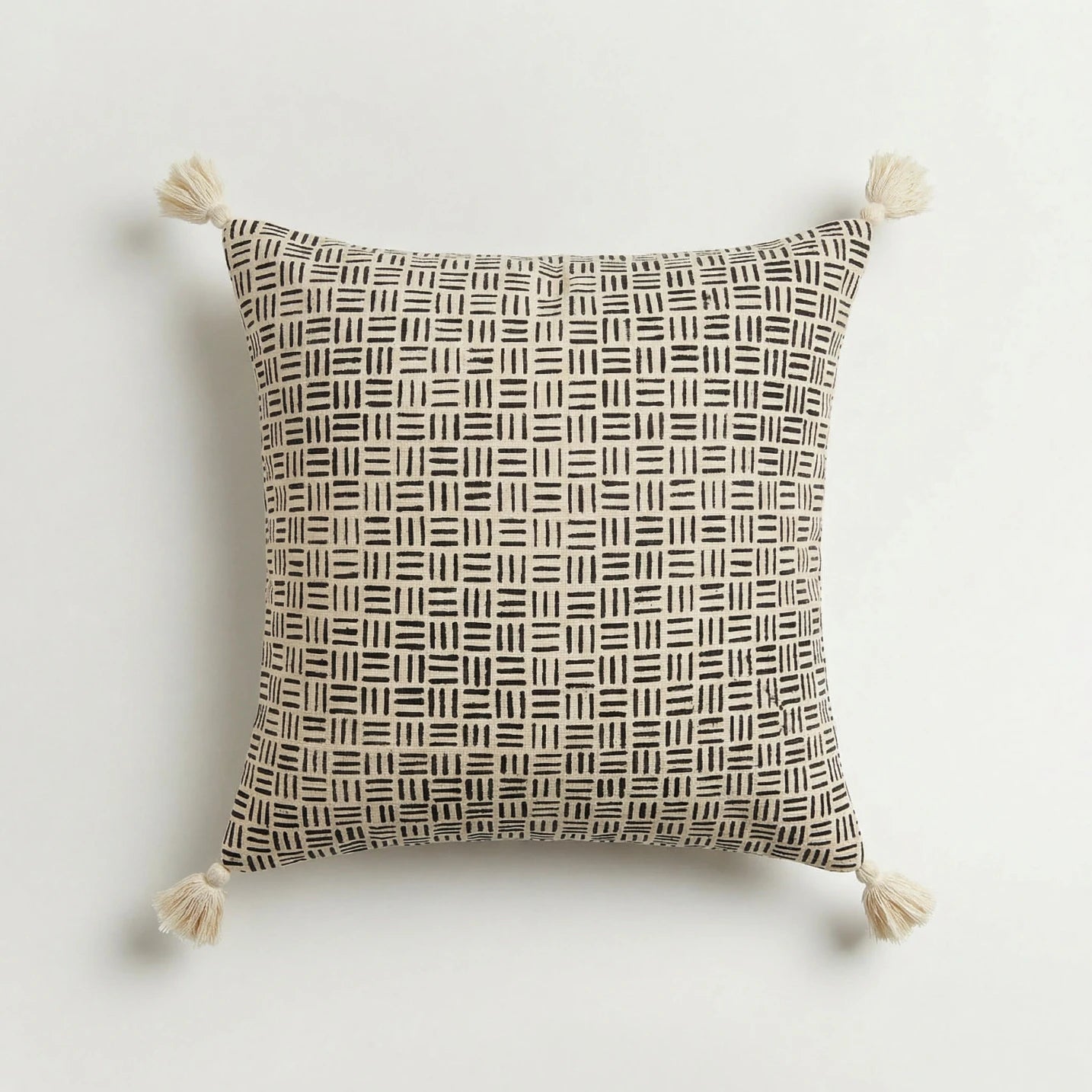 Decorative pillow with geometric pattern and tassels on a light background