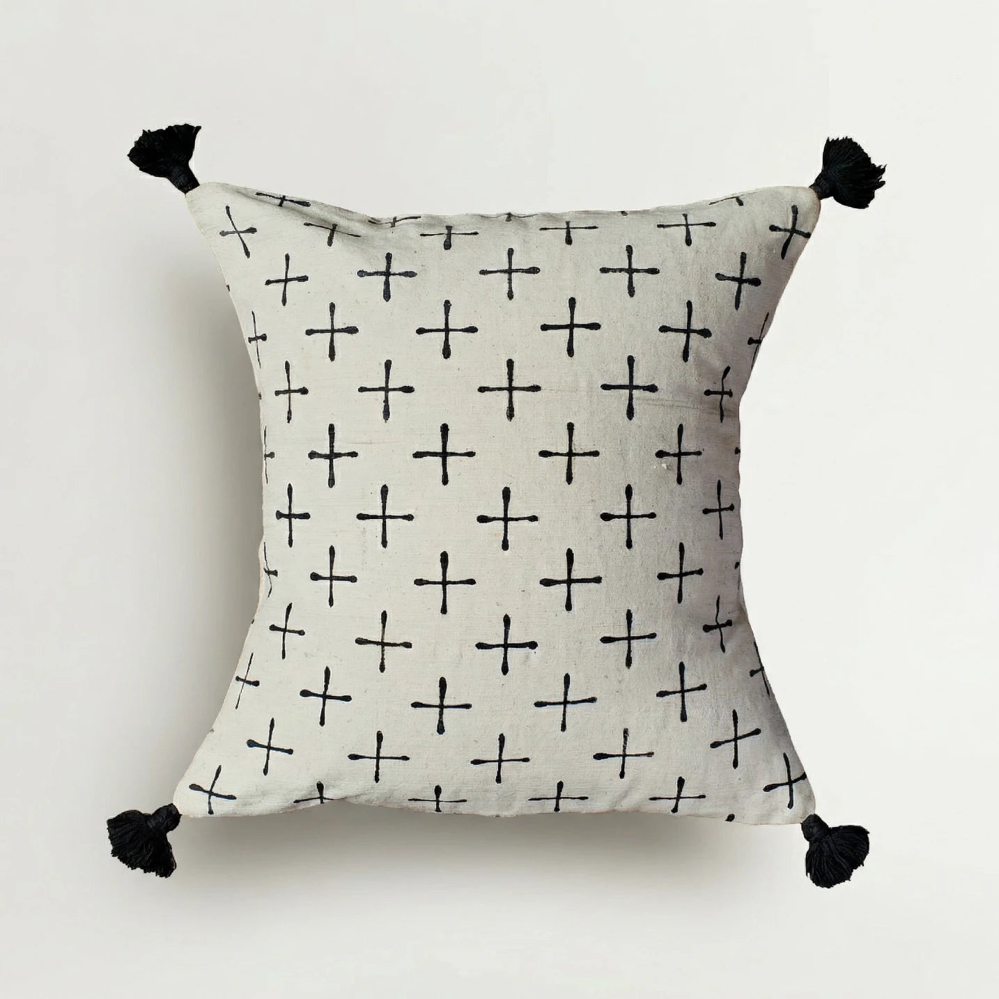 Decorative pillow with black cross pattern and tassels on a white background