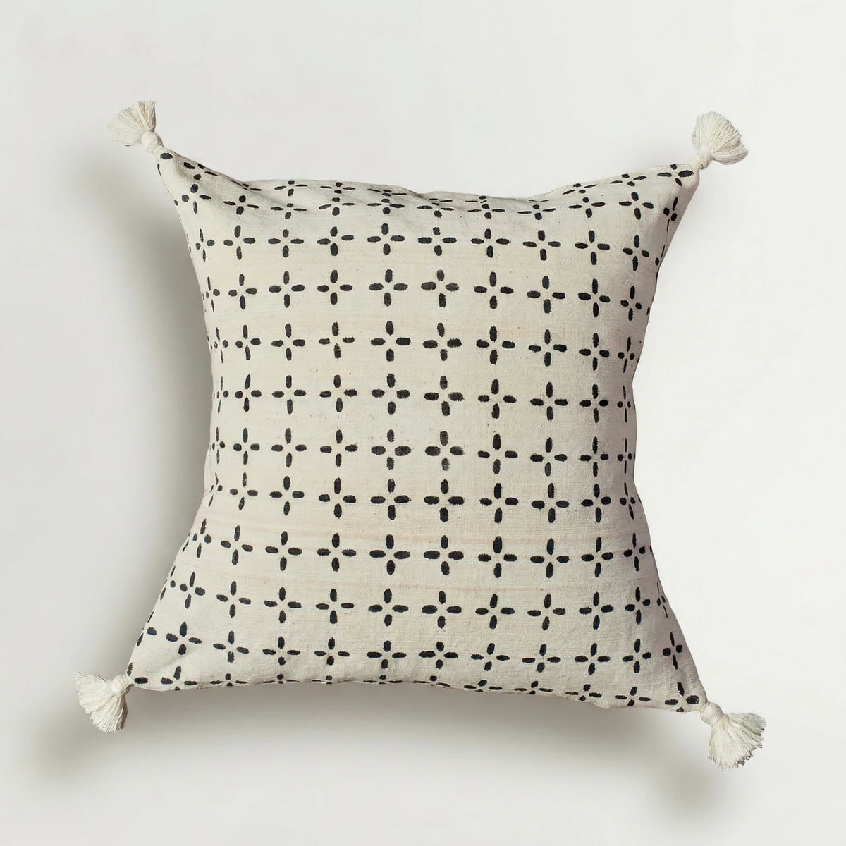 Decorative pillow with black geometric pattern and white tassels on a light gray background