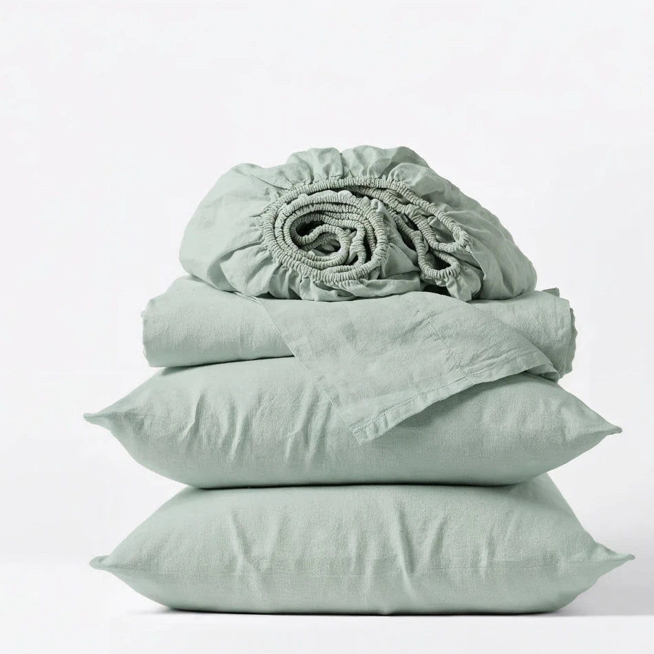 Set of light green bedding including a fitted sheet, two pillows, and a duvet on a white background
