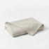 Folded beige blanket on a white background