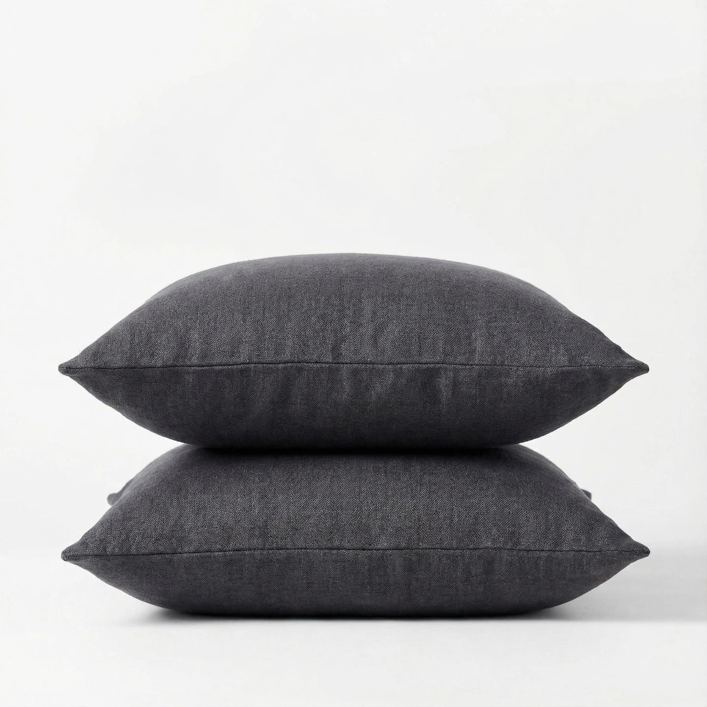 Two dark gray pillows stacked on a white background