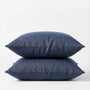 Two denim blue pillows stacked on a white background