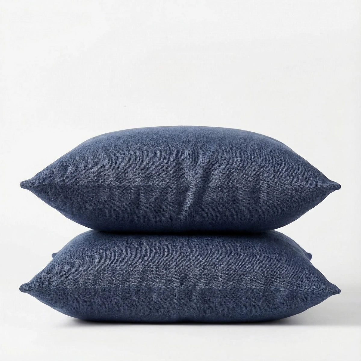 Two denim blue pillows stacked on a white background