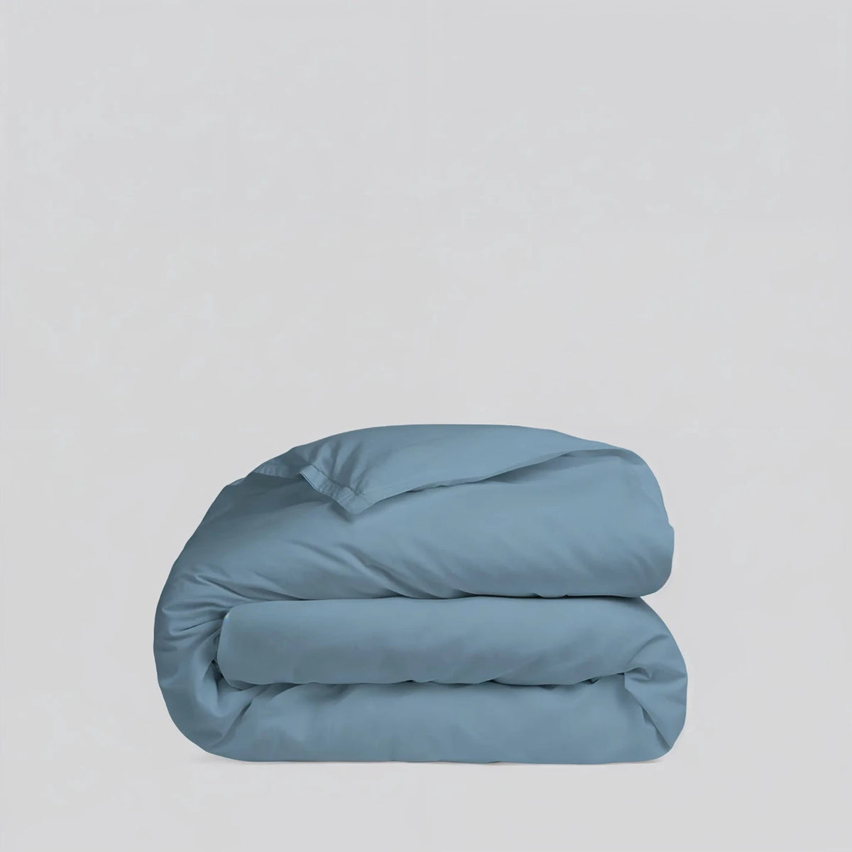 Folded blue comforter on a light gray background