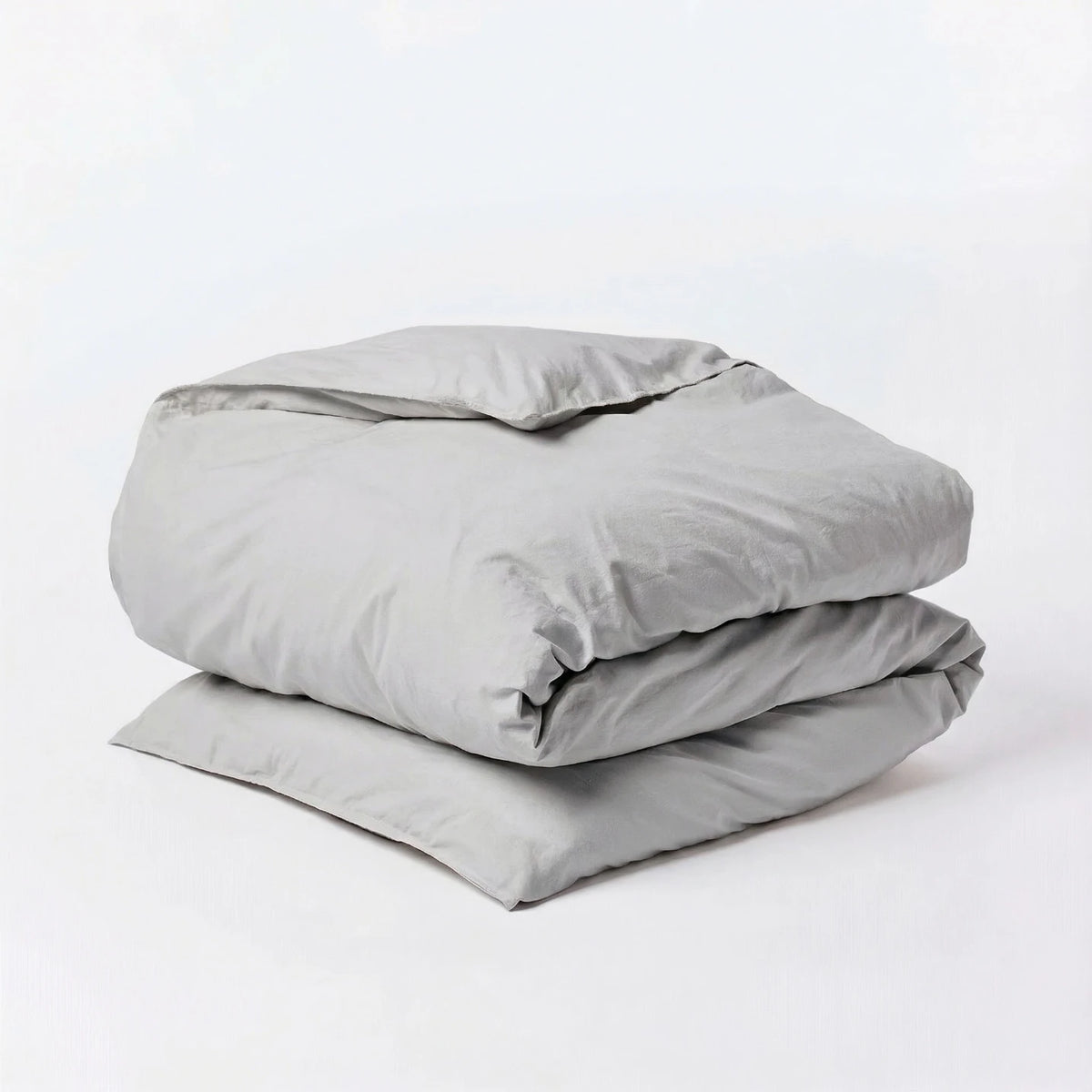 Stack of light gray comforters on a white background